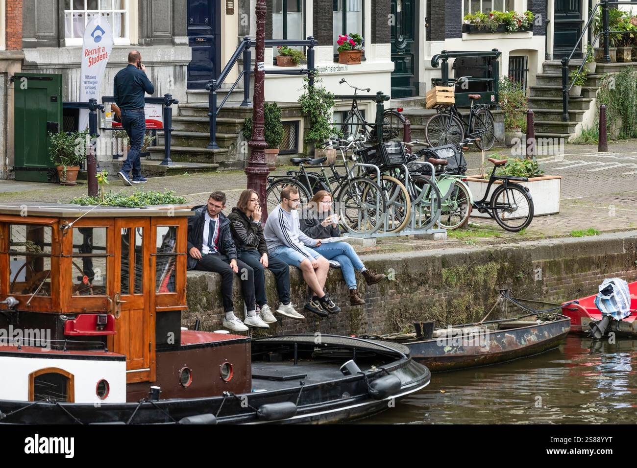 I giovani potranno gustare un panino sulla parete del canale di Amsterdam. Foto Stock
