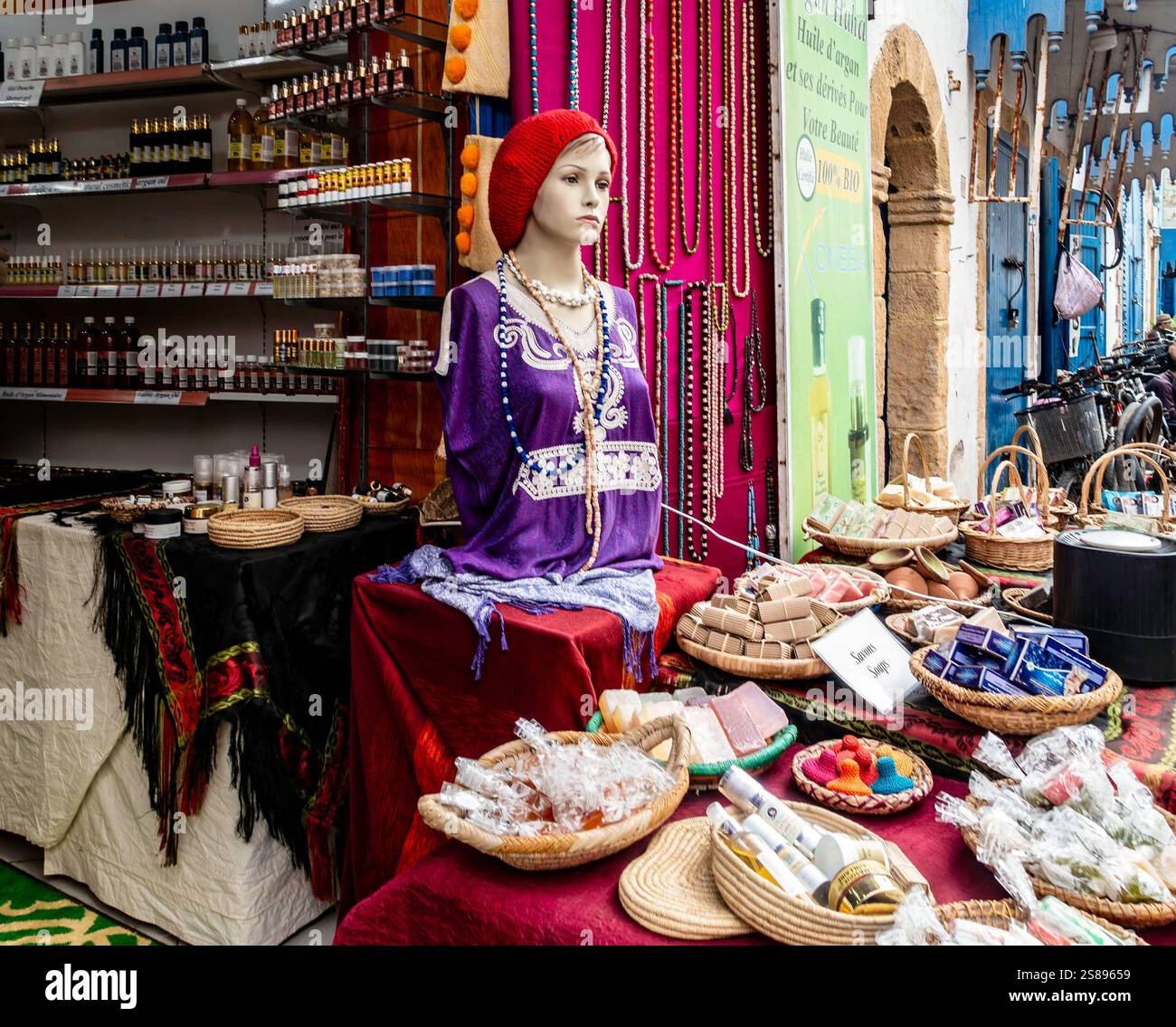 Un colorato bancarello del mercato espone artigianato, erbe e saponi artigianali e abbigliamento tradizionale nel suk di Essaouira, Marocco. Foto Stock