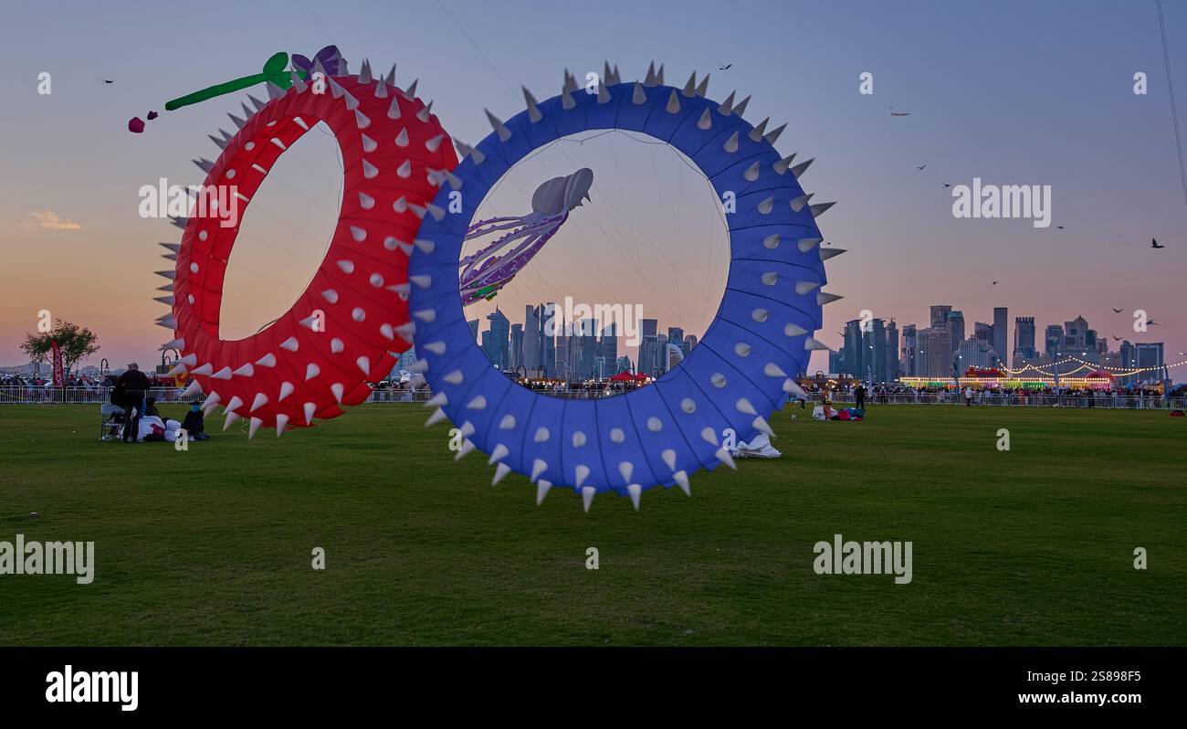 Qatar Kite Festival 2025 nel porto vecchio di Doha (quartiere Mina) foto al tramonto che mostra una spettacolare vetrina di aquiloni colorati che si innalzano sullo skyline di Doha Foto Stock