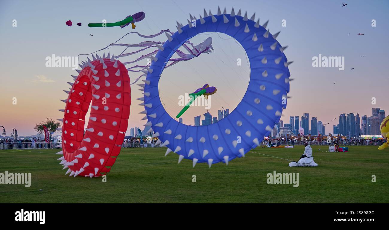 Qatar Kite Festival 2025 nel porto vecchio di Doha (quartiere Mina) foto al tramonto che mostra una spettacolare vetrina di aquiloni colorati che si innalzano sullo skyline di Doha Foto Stock