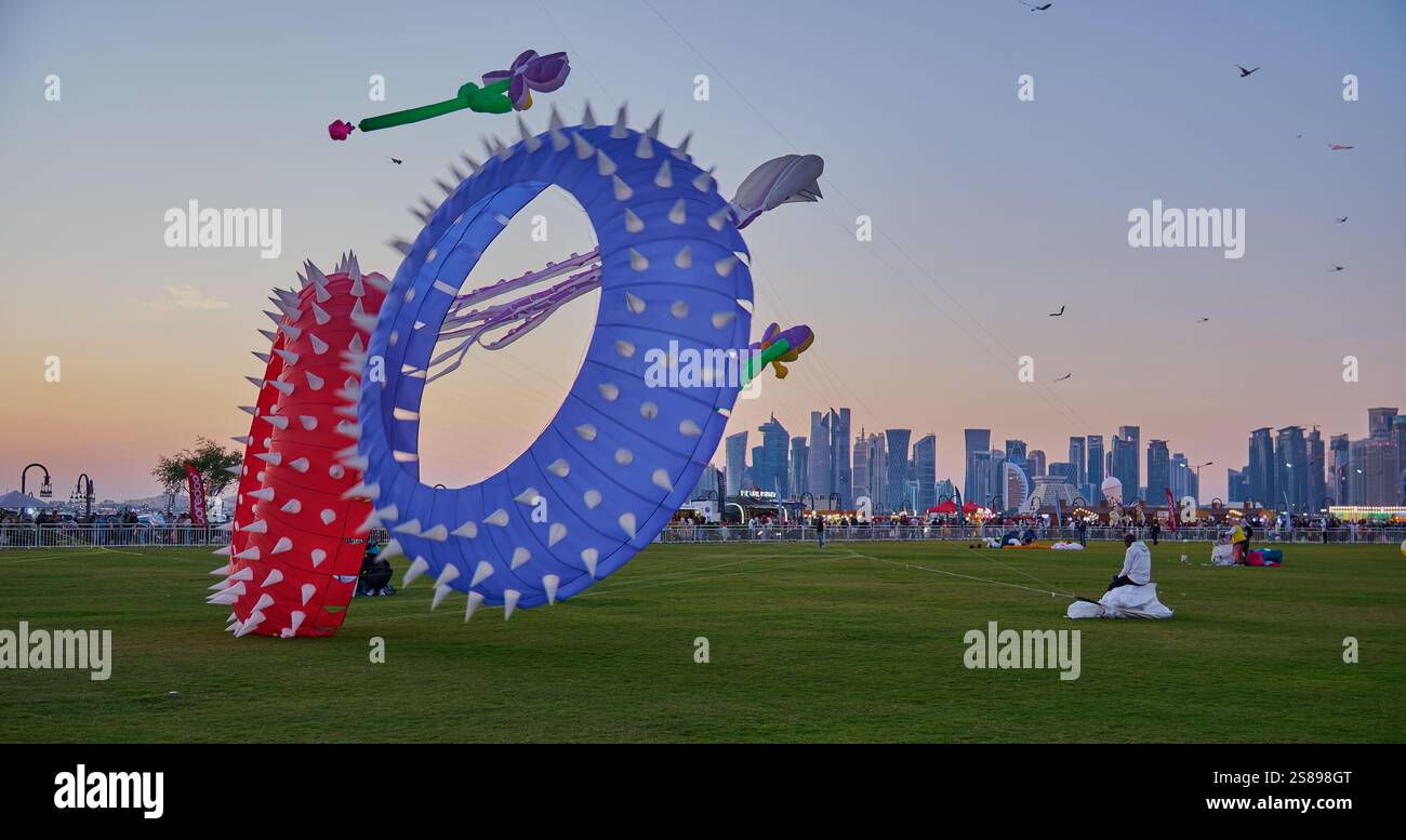 Qatar Kite Festival 2025 nel porto vecchio di Doha (quartiere Mina) foto al tramonto che mostra una spettacolare vetrina di aquiloni colorati che si innalzano sullo skyline di Doha Foto Stock