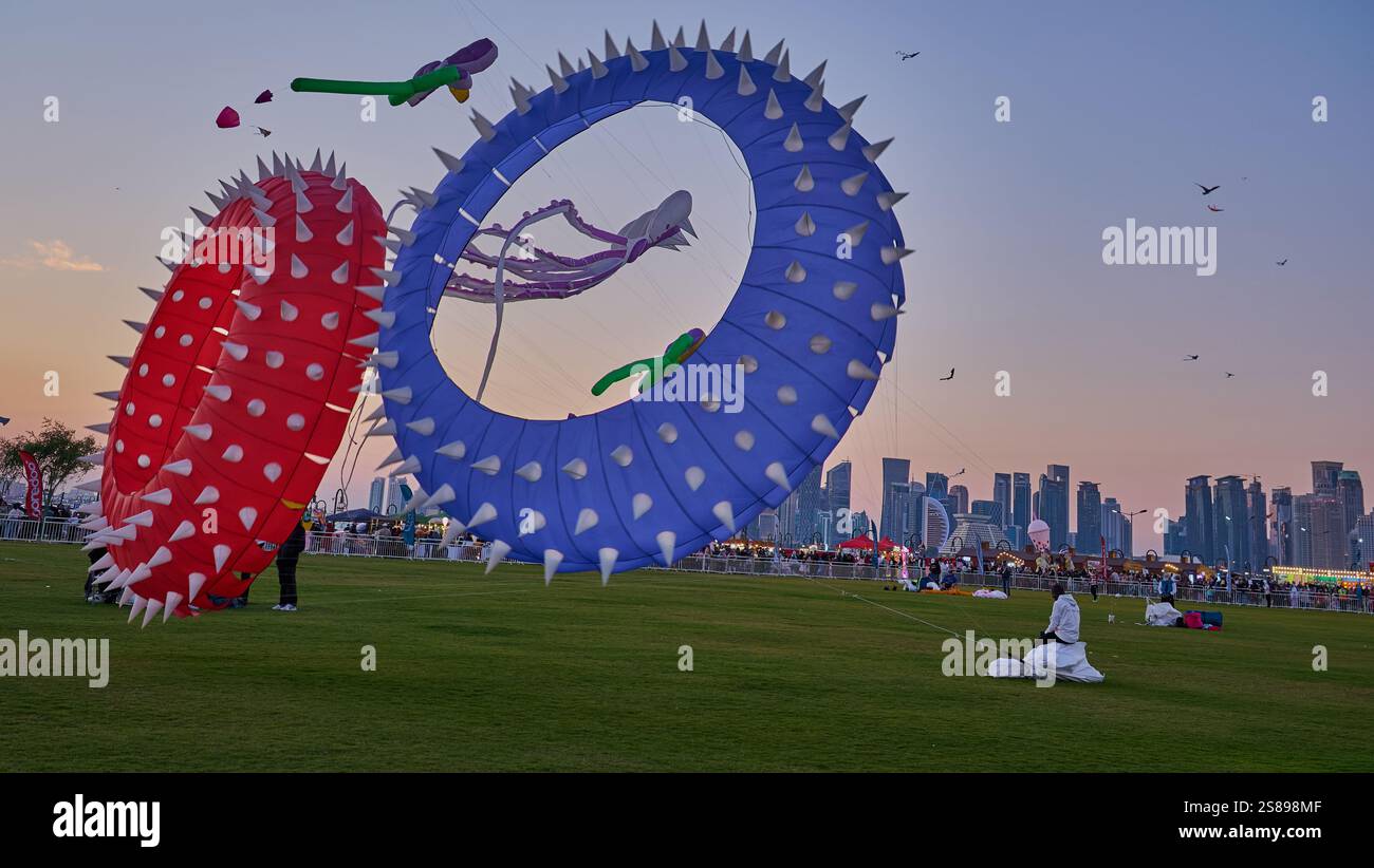 Qatar Kite Festival 2025 nel porto vecchio di Doha (quartiere Mina) foto al tramonto che mostra una spettacolare vetrina di aquiloni colorati che si innalzano sullo skyline di Doha Foto Stock