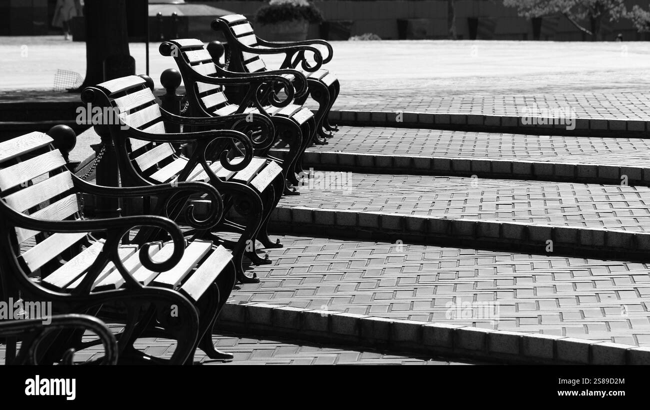 Panche allineate sui gradini graduali della piazza Foto Stock