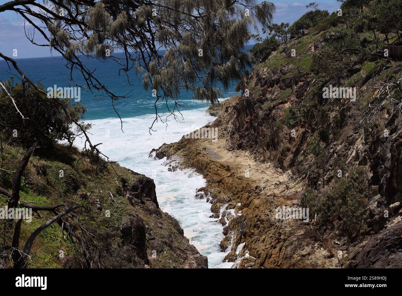 l'acqua bianca delle onde blu dell'oceano riempie uno stretto canale tra gli affioramenti rocciosi Foto Stock