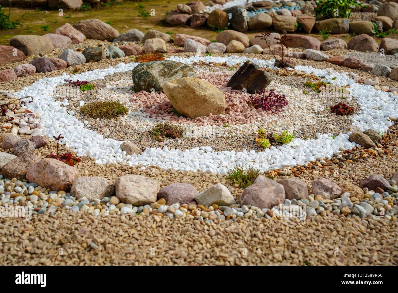 Giardino di ciottoli e pietre con bordo di pietra centrale e ghiaia bianca Foto Stock