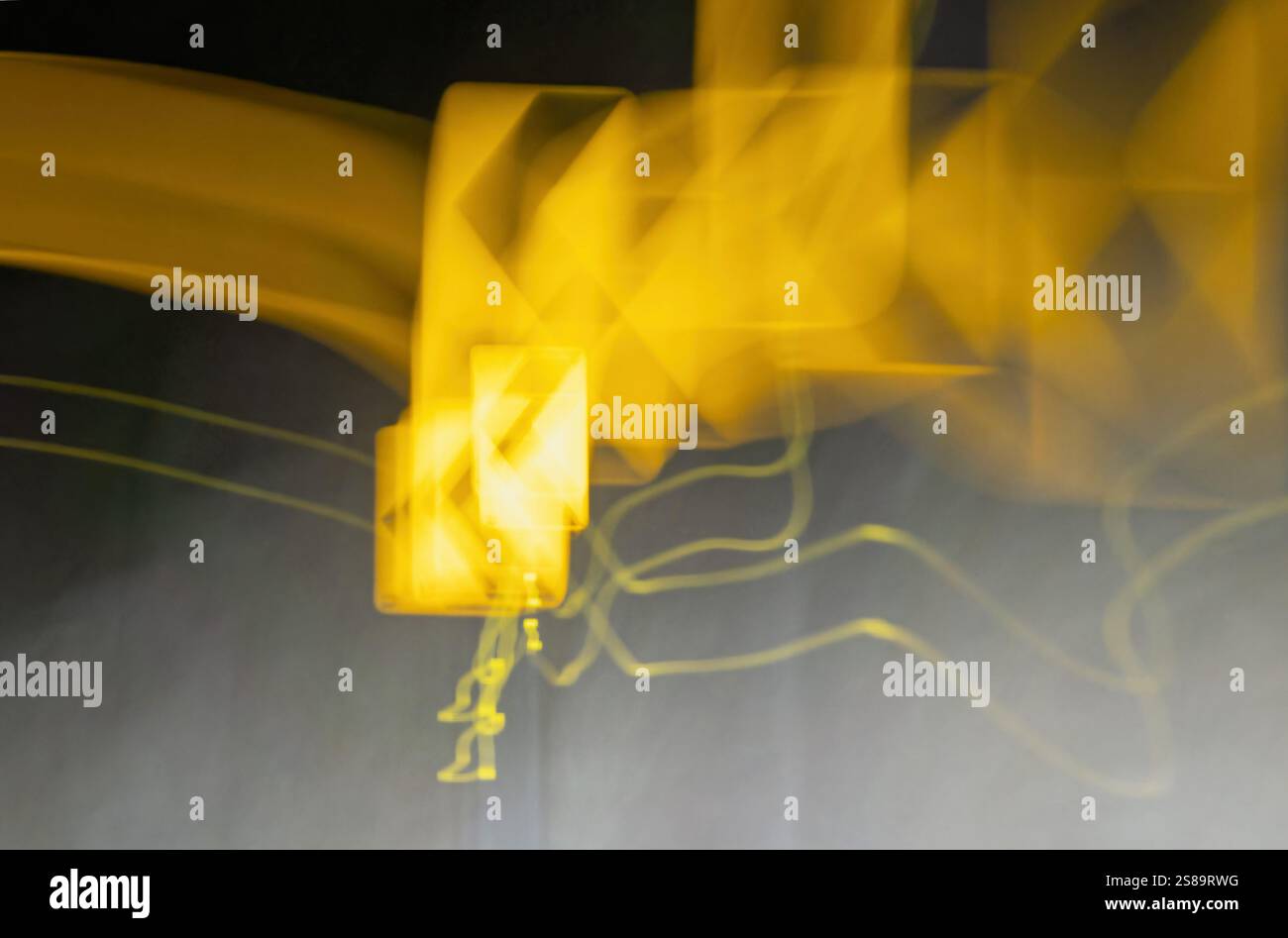 Le linee gialle brillanti si attorcigliano e girano, creando forme fluide e astratte su uno sfondo scuro. Il movimento suggerisce energia e dinamismo, come le forme Foto Stock