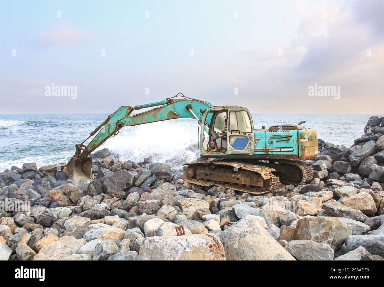 L'escavatore muove rocce per costruire frangiflutti per la protezione costiera a Glagah Beach il 21 ottobre 2011 a Glagah Beach a Yogyakarta Foto Stock