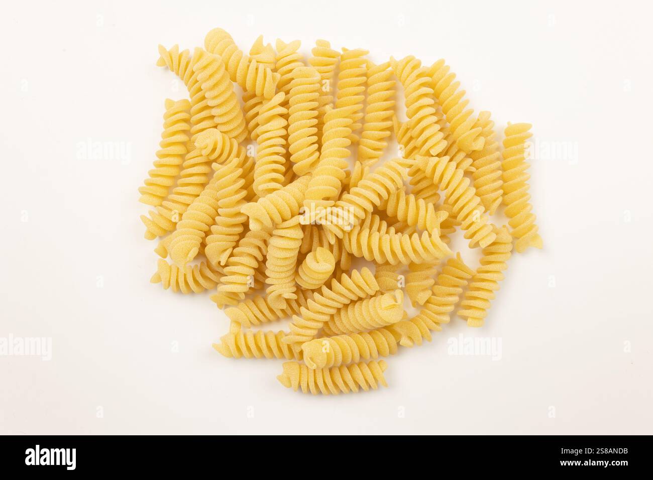 mucchio di fusilli crudi, primo piano, isolati su sfondo bianco Foto Stock