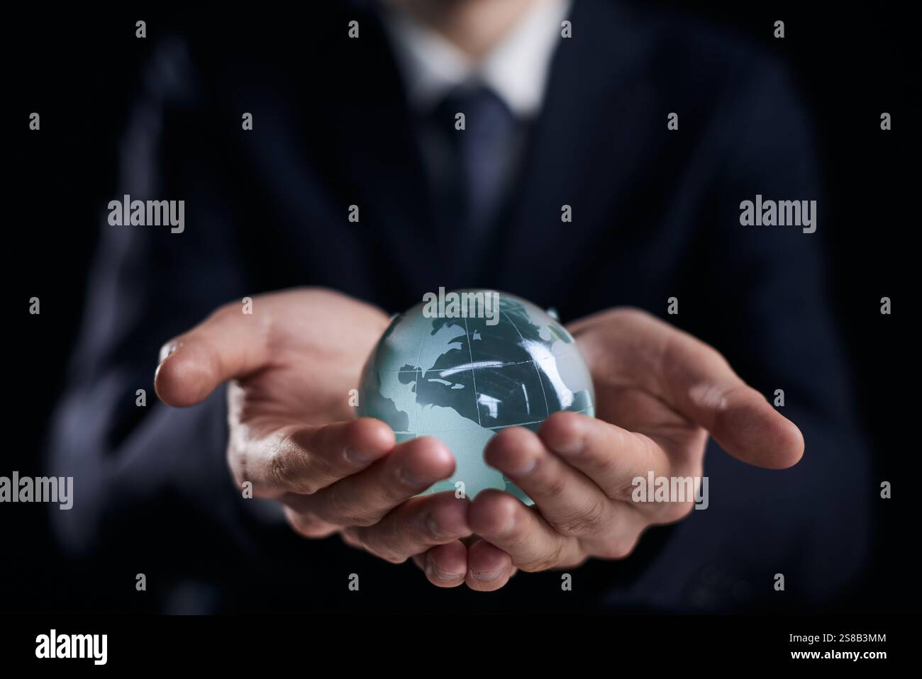 un uomo d'affari tiene il globo di vetro con i continenti in mano Foto Stock
