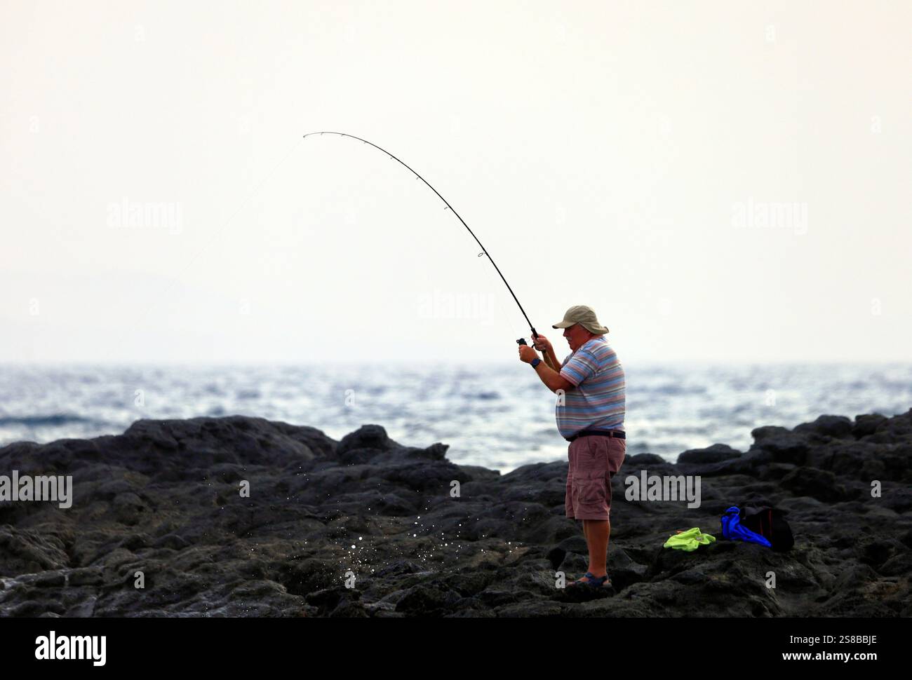 Angler Reeling in fish, El Cotillo, Fuerteventura, Isole Canarie, Spagna. Foto Stock