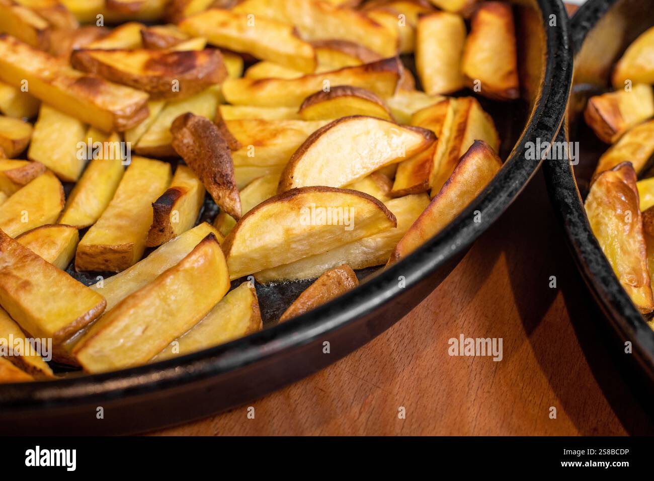 Patate cotte in padella su fondo di legno Foto Stock