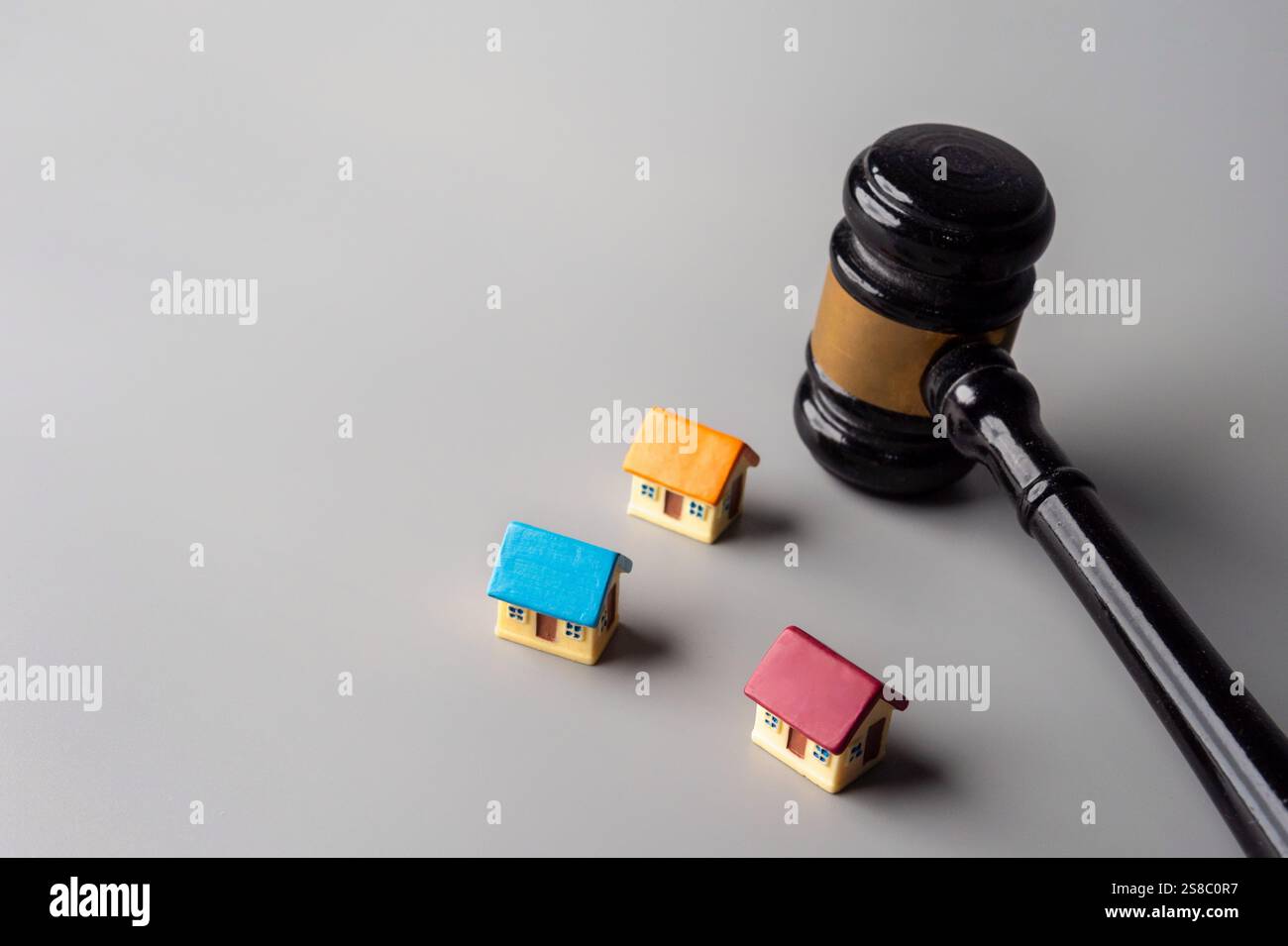 Un martelletto e case colorate in miniatura. Asta o preclusione immobiliare, concetto di diritto immobiliare. Foto Stock