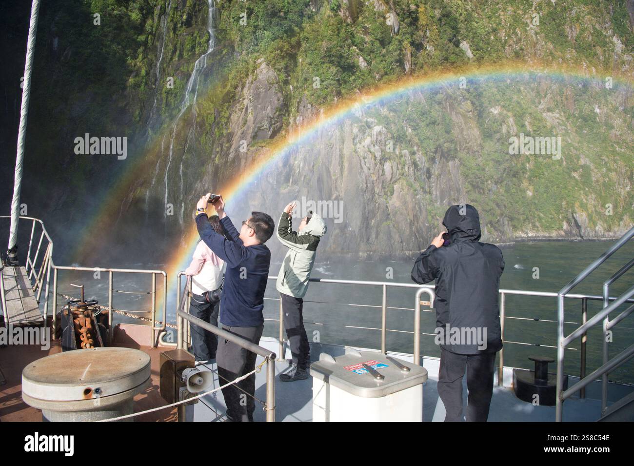I turisti fotografano le cascate e il doppio arcobaleno a Milford Sound, South Island, nuova Zelanda Foto Stock