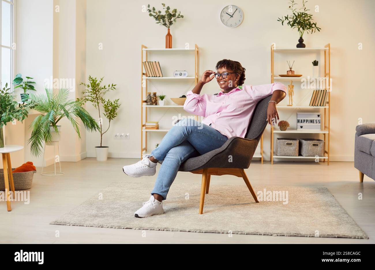 Ritratto di una donna afroamericana felice sorridente in poltrona a casa Foto Stock