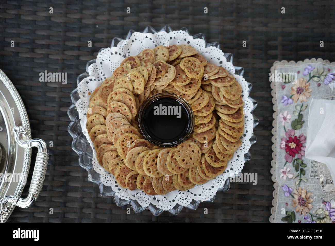 Un piatto splendidamente organizzato di mini pancake tradizionali serviti con una ciotola di ricco sciroppo di dattero. Perfetto per gustare la cucina culturale, durante le feste Foto Stock