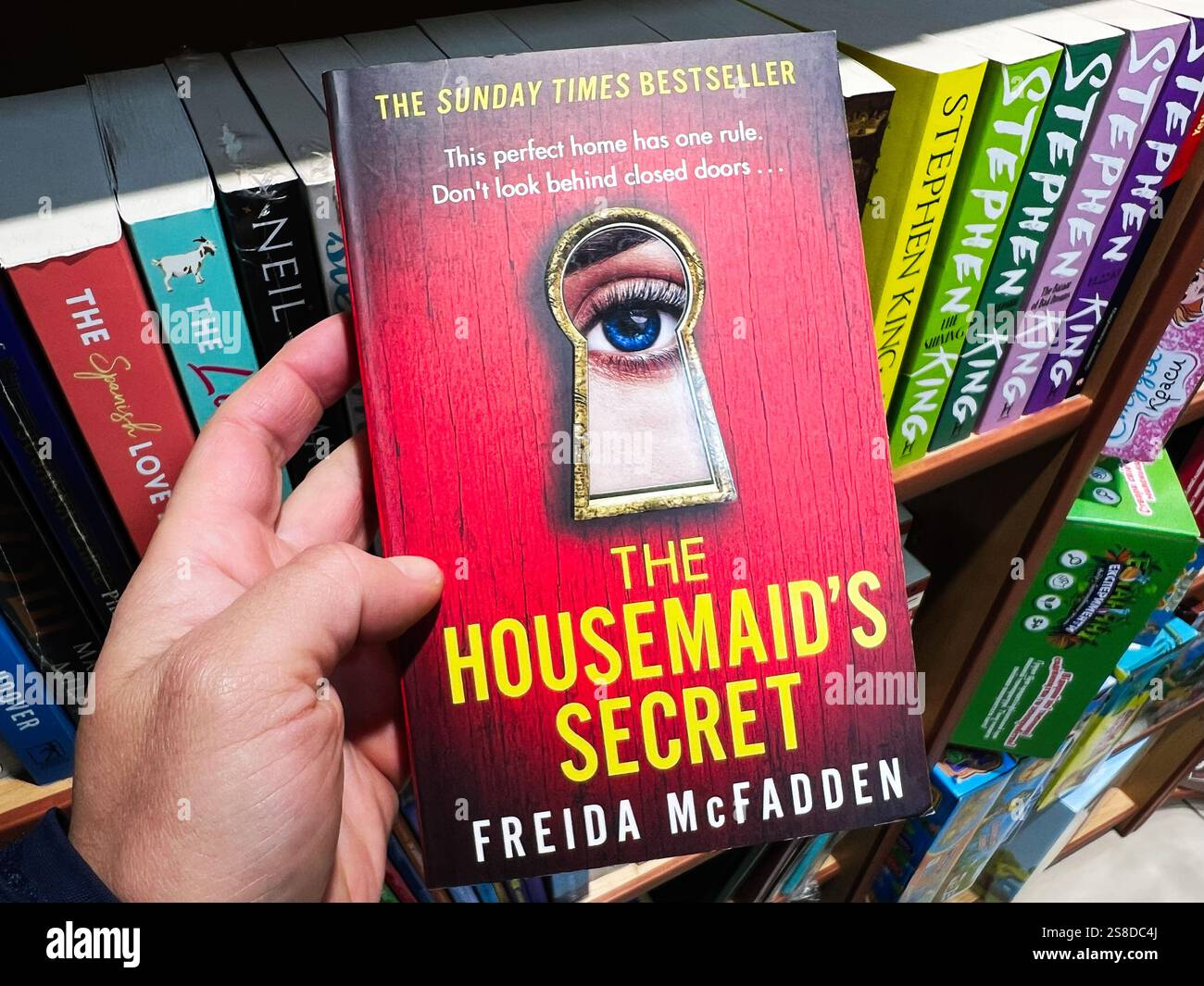 Kiev, Ucraina - 21 gennaio 2025: Un primo piano di una mano che tiene in mano il romanzo di suspense "il segreto della Housemaid" di Freida McFadden, esposto in un bookstor Foto Stock