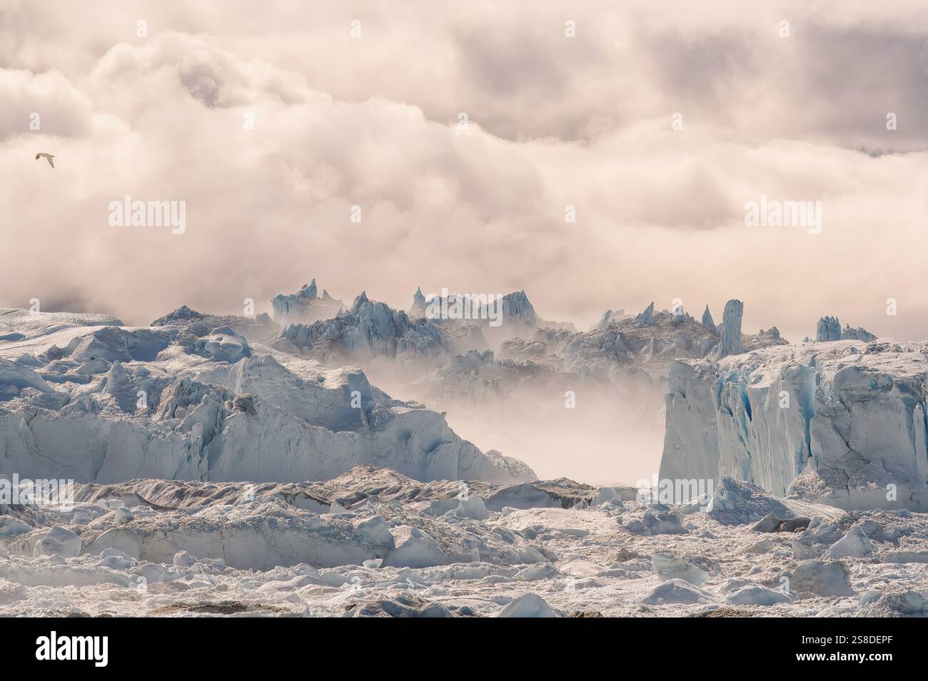 Torreggianti iceberg sorgono dal mare, parzialmente avvolti dalla nebbia, creando un'atmosfera eterea a Ilulissat, Avannaata, Groenlandia. Foto Stock