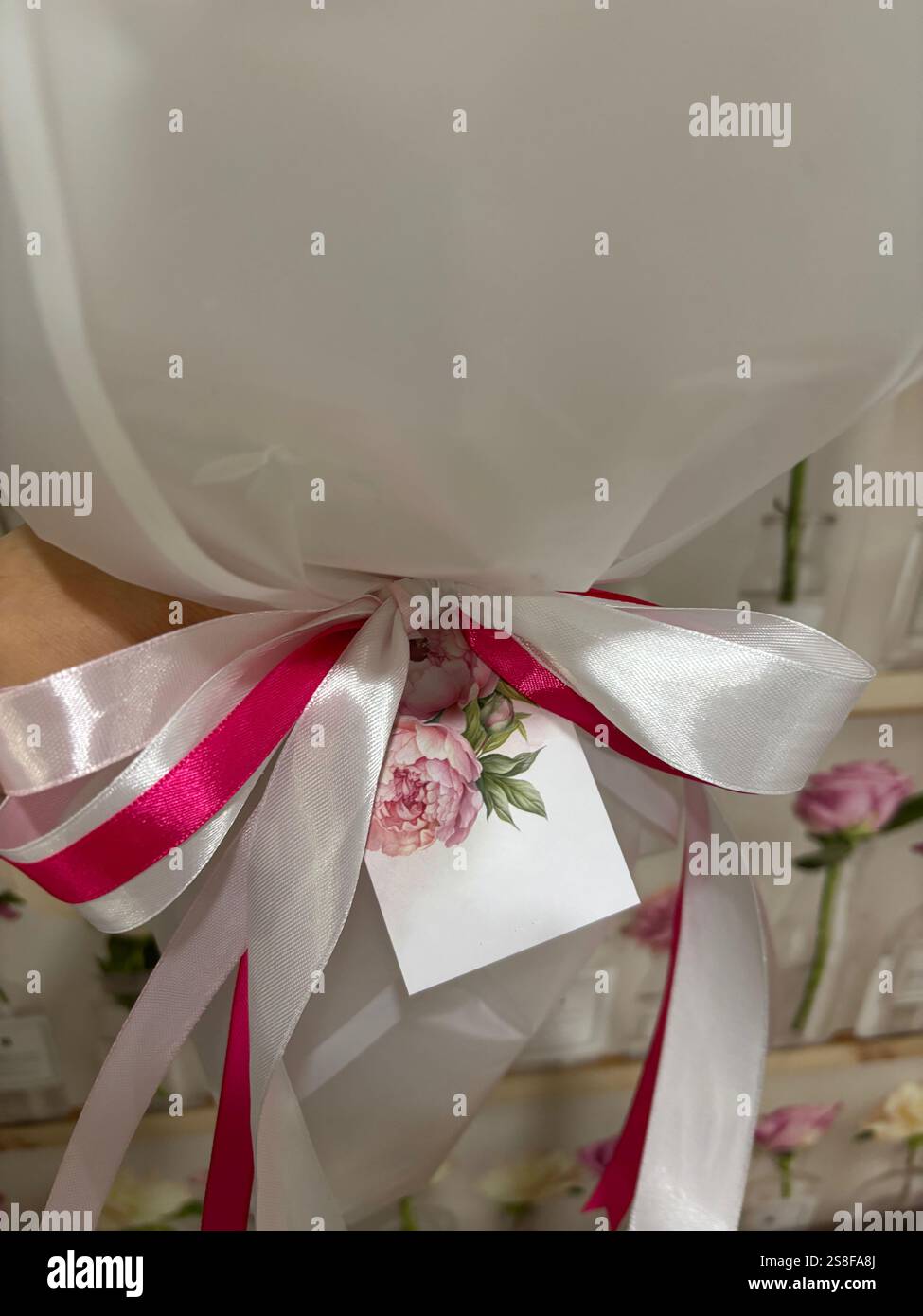 Un frammento di bouquet. Un nastro legato a un fiocco e un'etichetta con marchio. Primo piano. Foto Stock