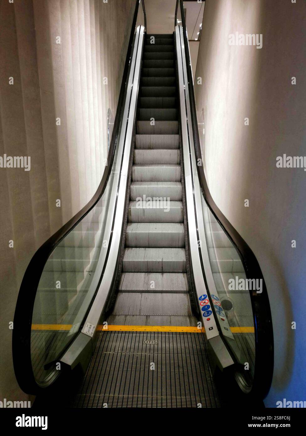 Scala mobile che conduce al piano superiore di un edificio moderno, illuminato e progettato per un movimento fluido Foto Stock