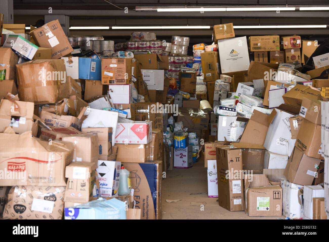 Magazzino pieno di scatole di cartone con merci pronte per essere distribuite nell'area interessata dalle inondazioni DANA. Scatole di cartone con prodotti impilati. Alfafar, Spagna Foto Stock