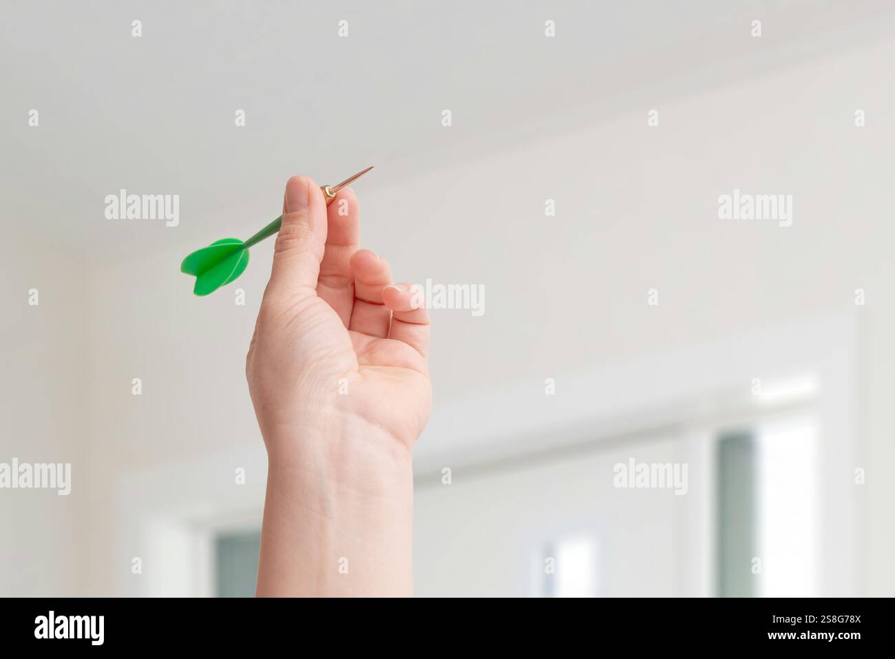 Mano che tiene un dardo, pronto a lanciare, simboleggia la messa a fuoco, la prontezza e l'azione strategica necessaria per raggiungere gli obiettivi con precisione e intento Foto Stock