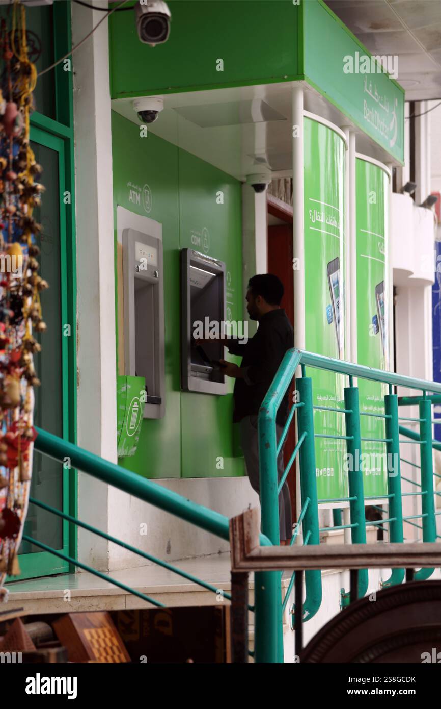 Uomo che usa Bank Dhofar ATM Nr Mutrah Market Corniche Muscat Oman Foto Stock