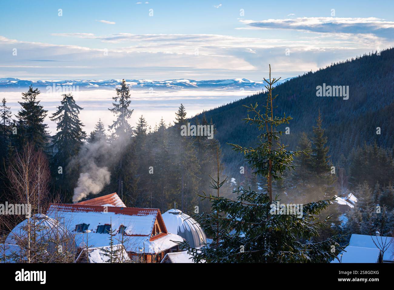 Vista panoramica invernale di montagne lontane e nebbia nella valle dal villaggio di Harghita-Băi (ungherese: Hargitafürdő), Romania. Foto Stock