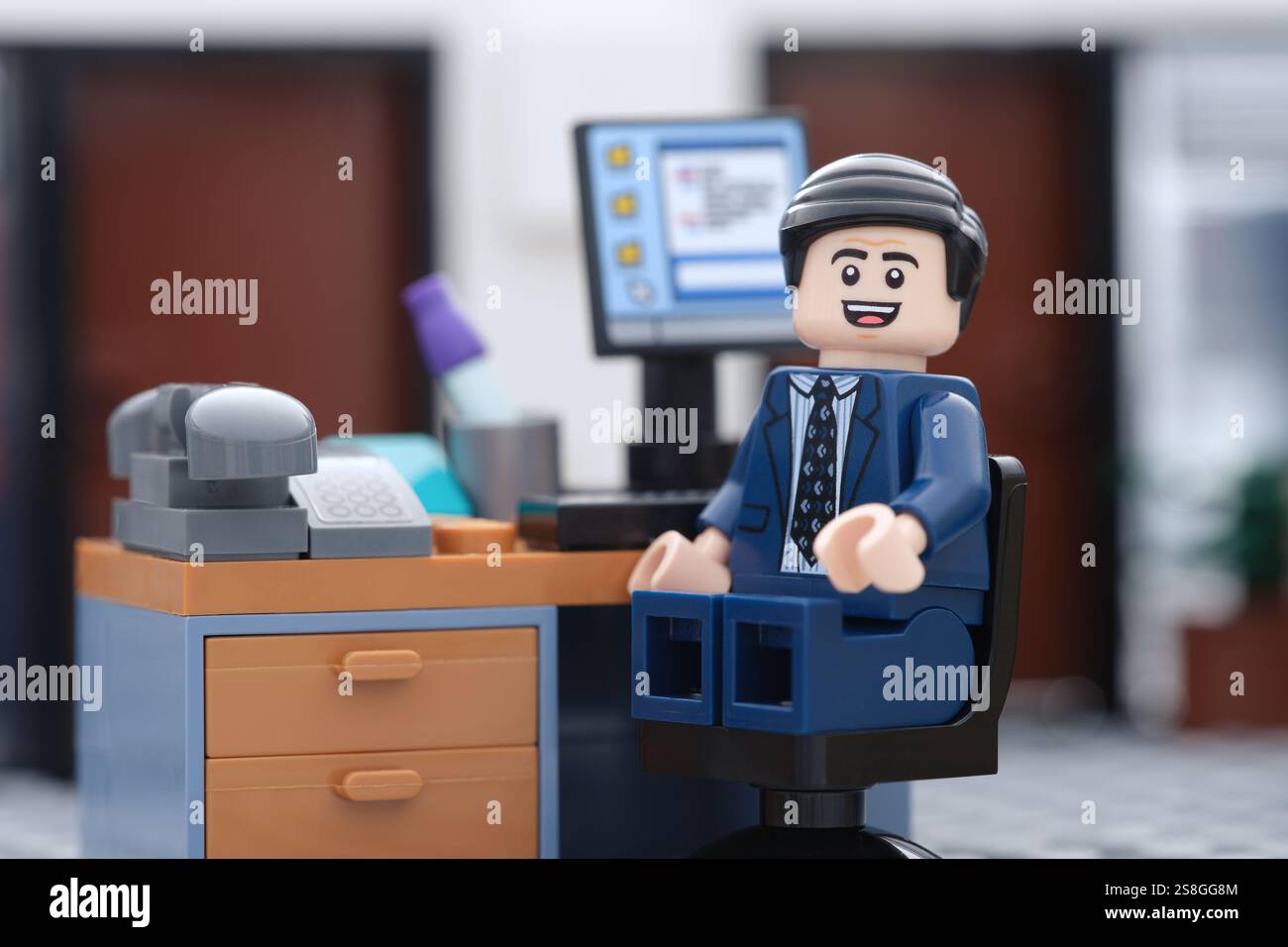 Tambov, Federazione Russa - 22 gennaio 2025 Un uomo d'affari felice Lego, seduto su una sedia dietro un computer in un ufficio e guardando il Foto Stock