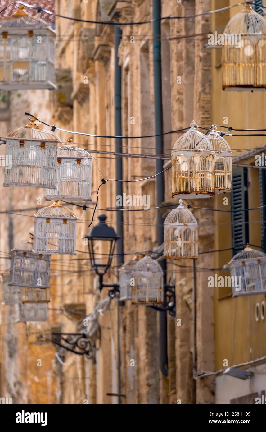 Gabbia per uccelli con lampadine su linee elettriche tra case sopra la strada, centro storico, Alghero, Europa, Provincia di Sassari, Italia Foto Stock