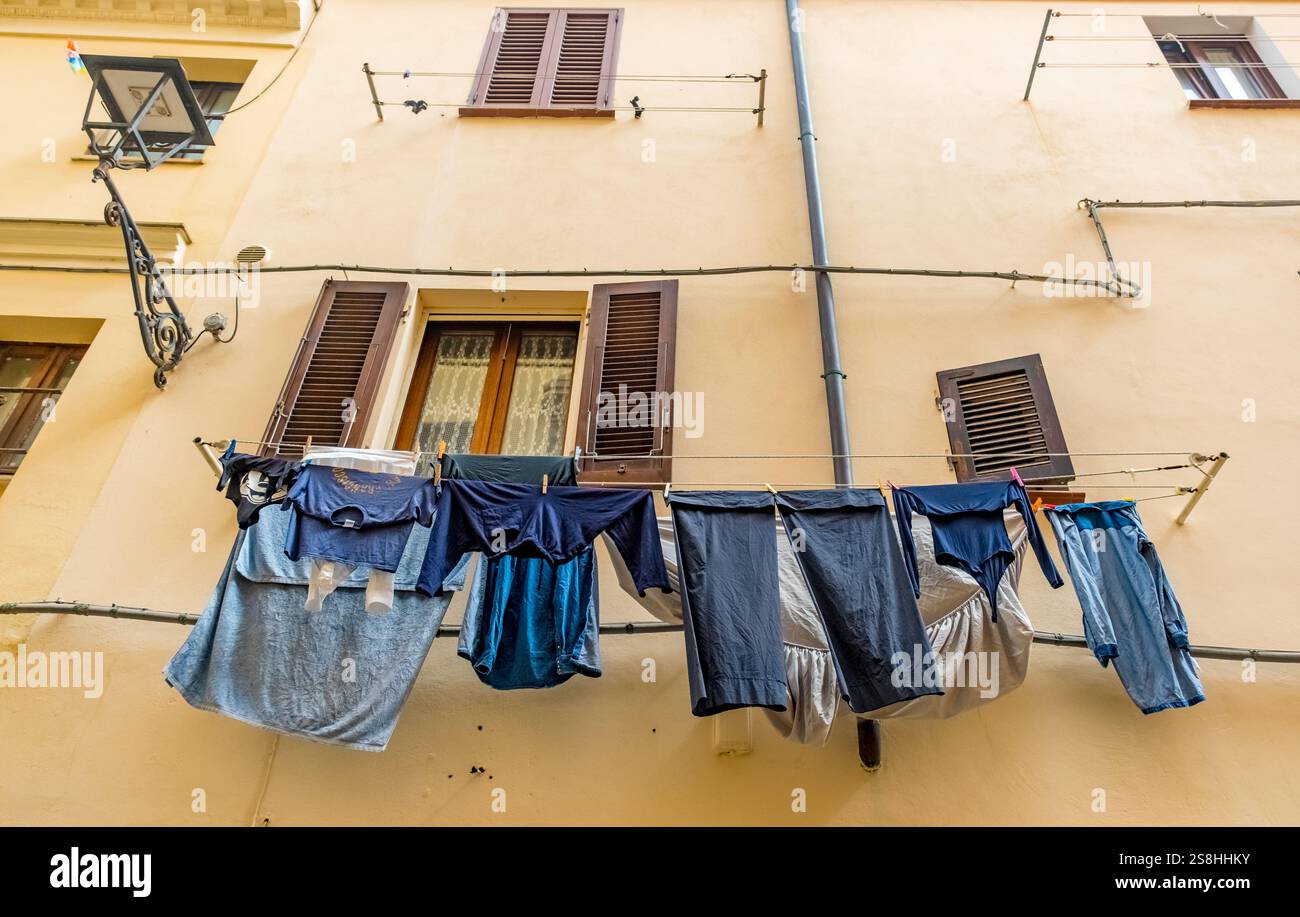 Clothesline con capi di abbigliamento su un muro di casa con finestre e persiane, Alghero, Europa, Provincia di Sassari, Italia Foto Stock