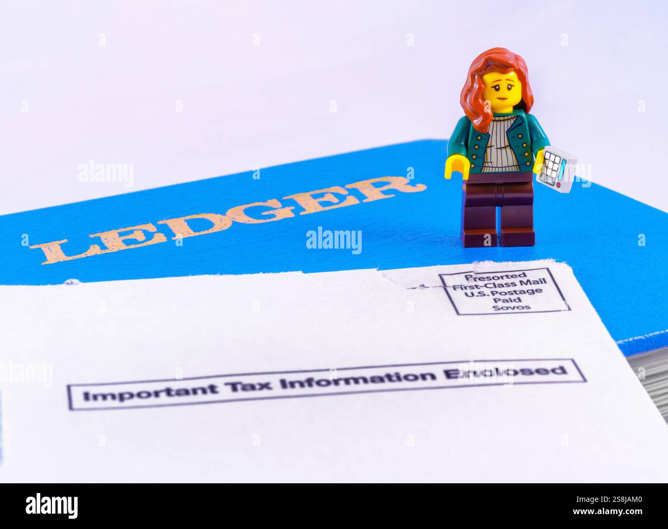 Chappaqua, NY - 11 aprile 2024: Concetto di giornata dell'imposta sul reddito Lego minifigure commercialista con libro di registro e busta IRS che dice importanti informazioni fiscali Foto Stock
