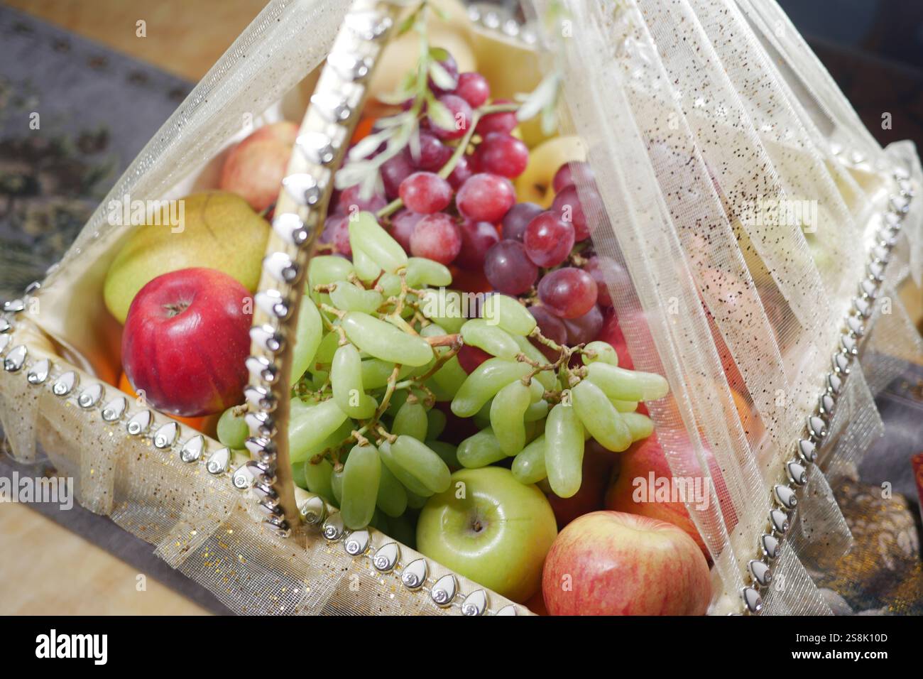Un elegante cestino di frutta riempito con un delizioso assortimento di frutta fresca Foto Stock