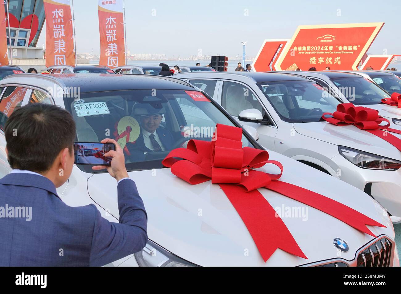 YANTAI, CINA - 23 GENNAIO 2025 - i dipendenti premiati posano per una foto con la vettura premiata durante la cerimonia di premiazione del gruppo Jierui 2024 'Go Foto Stock