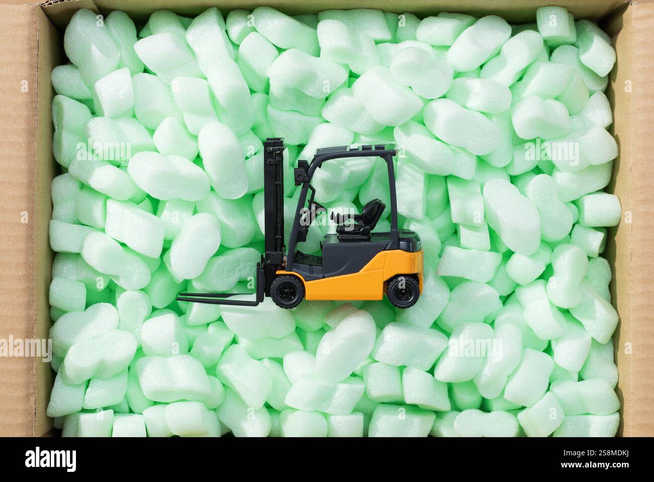 Carrello elevatore a forche in miniatura all'interno di una scatola di consegna piena di chip di imballaggio, consegna sicura e concetto logistico Foto Stock