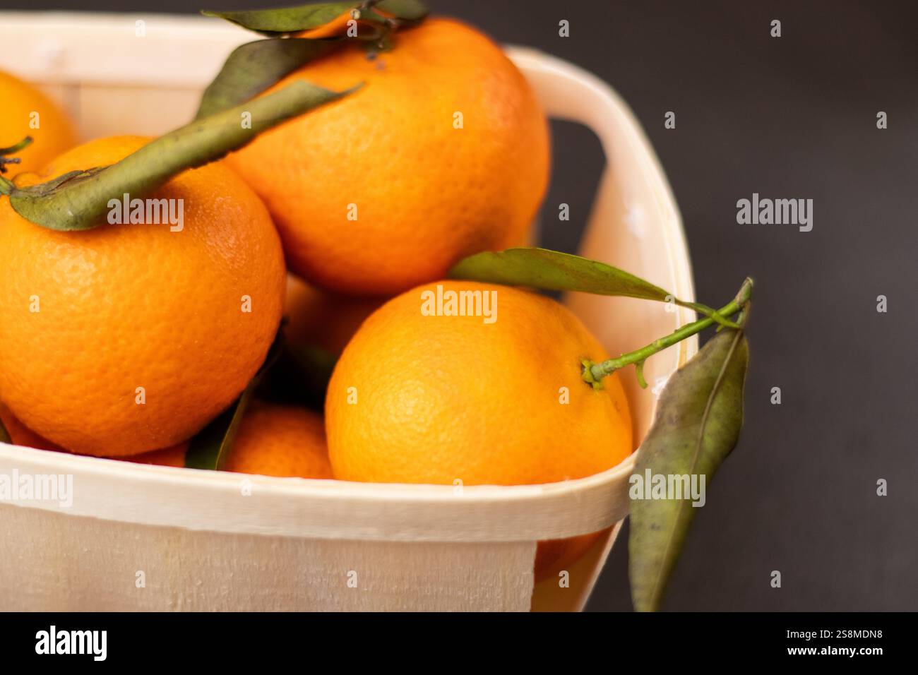 Primo piano di frutta mandarina in una scatola di legno su sfondo grigio Foto Stock
