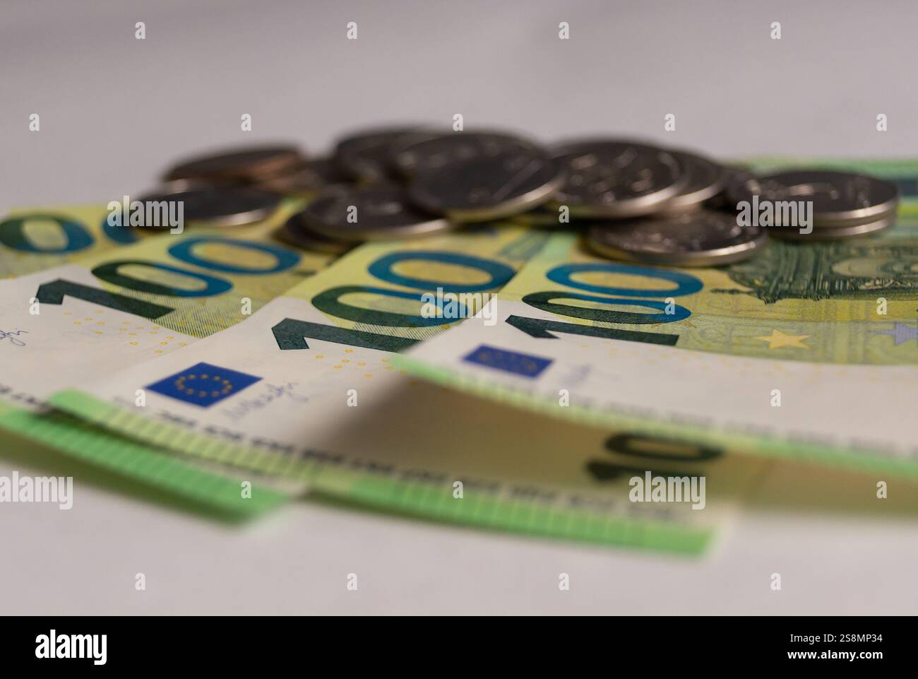 Primo piano sulle banconote in euro. primo piano 100 euro. (Valuta dell'Unione europea). In cima alle banconote ci sono le monete. Foto Stock