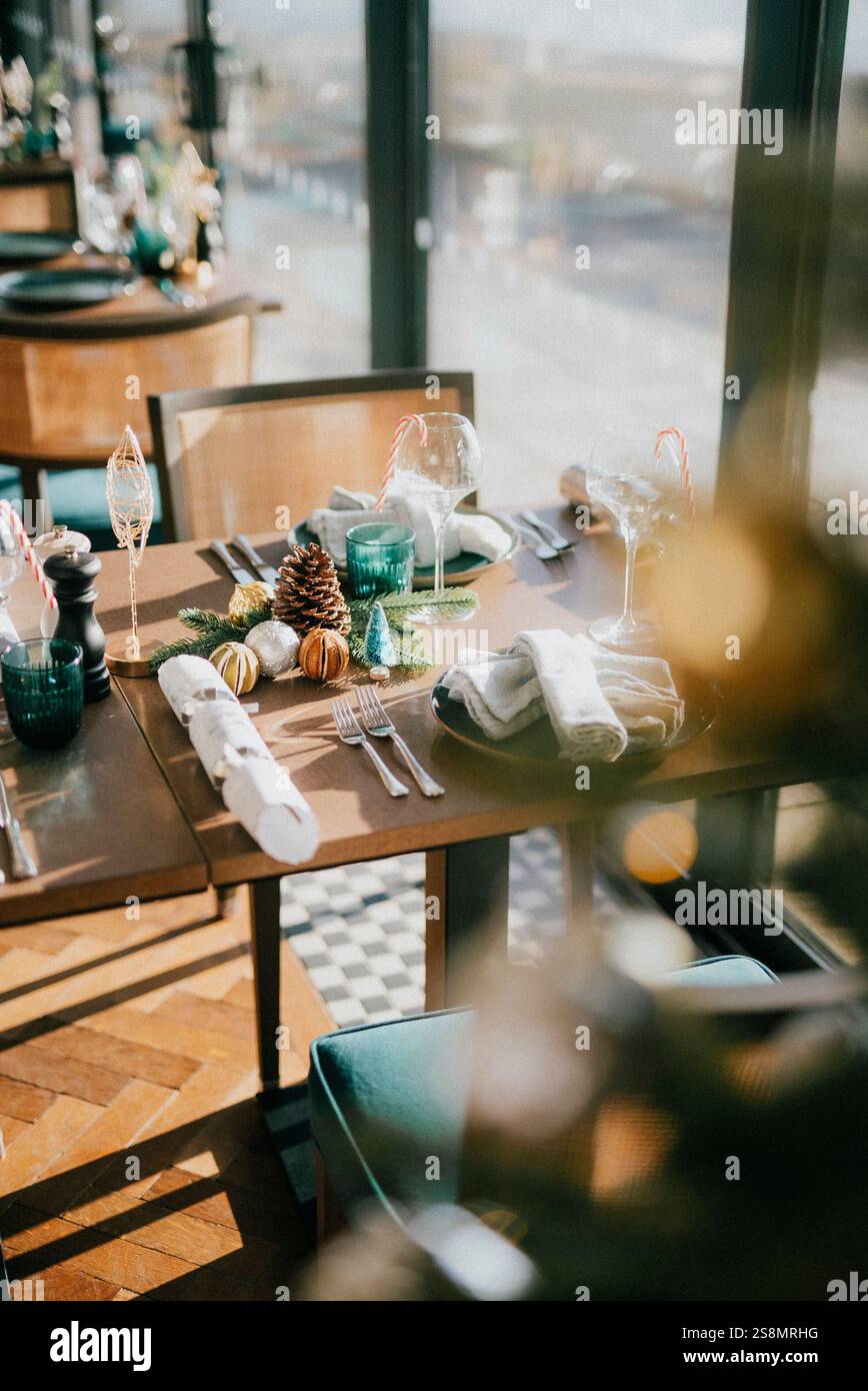 Un tavolo con un albero di Natale e una tovaglia con un tovagliolo bianco. Il tavolo e' allestito con una varieta' di utensili e bicchieri Foto Stock