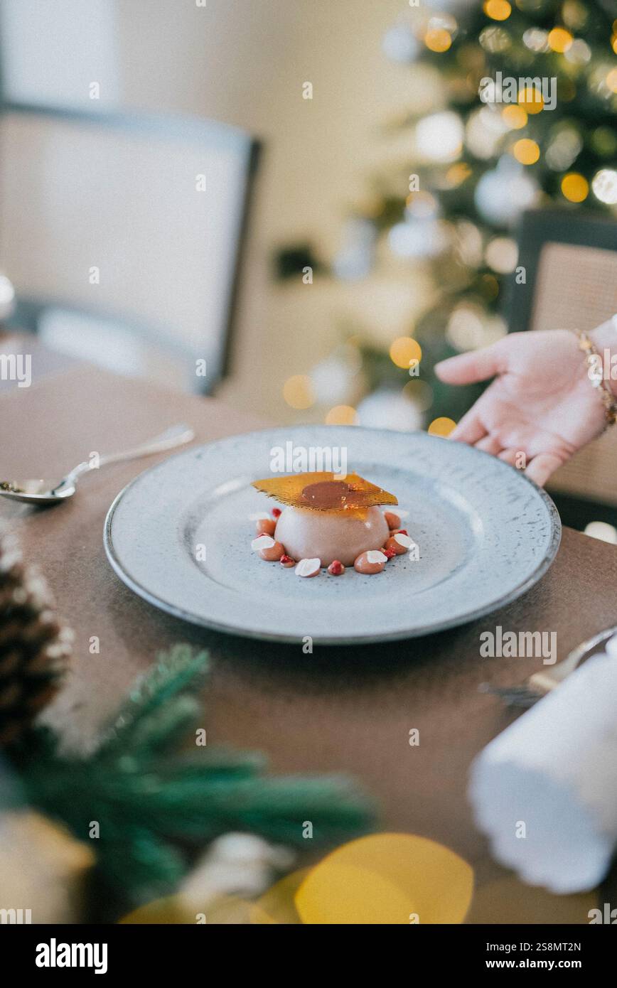 Un piatto di dessert con una mano che lo raggiunge. Il dessert è una torta con un condimento al caramello Foto Stock
