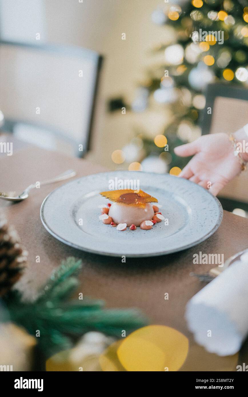 Un piatto di dessert con una mano che lo raggiunge. Il dessert è una torta con un condimento al caramello. L'immagine ha uno stato d'animo festivo, in quanto è allestita per un holi Foto Stock