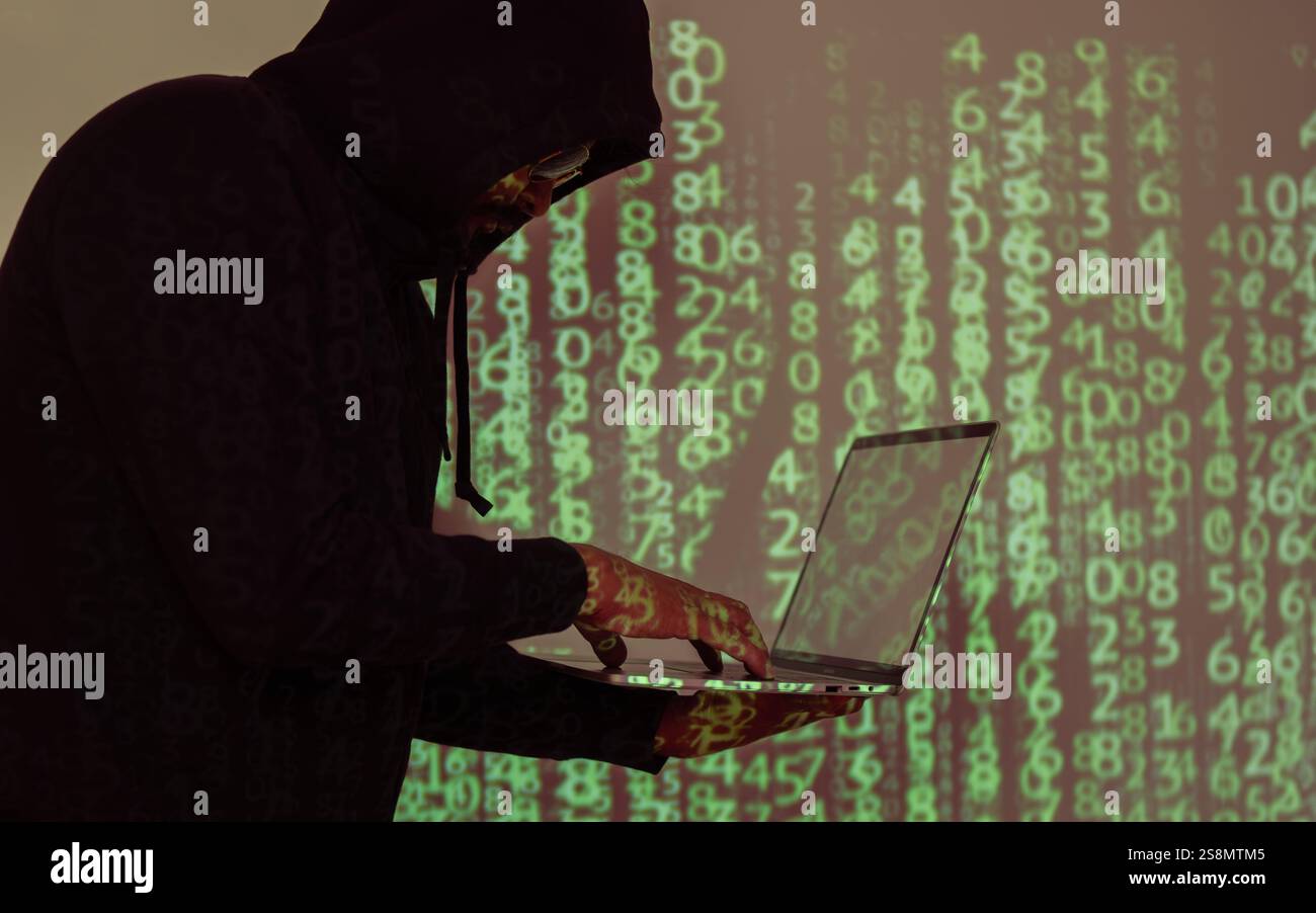 Vista laterale dell'hacker con cappuccio nero e laptop sullo sfondo digitale del codice binario. Prestare attenzione agli attacchi degli hacker. Foto Stock