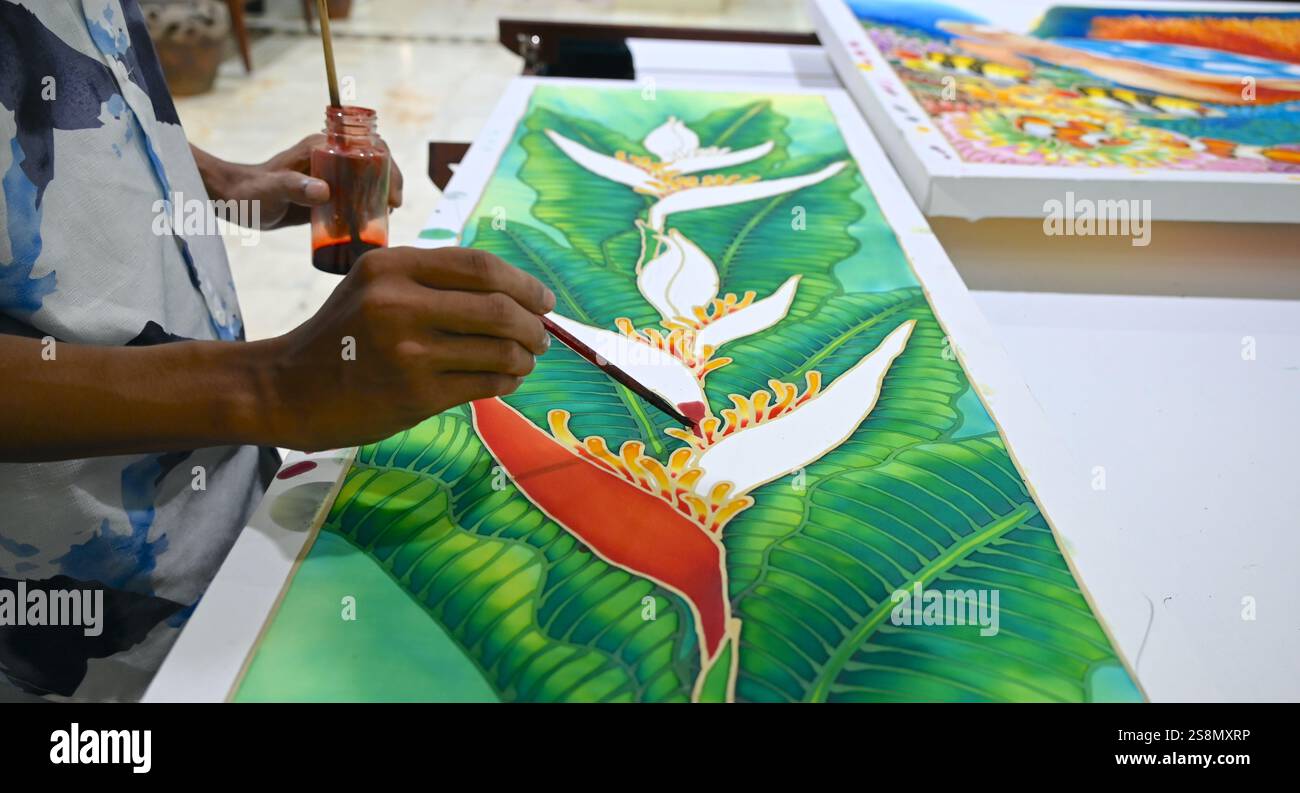 La persona disegna il batik con colori e pennelli colorati. Foto Stock