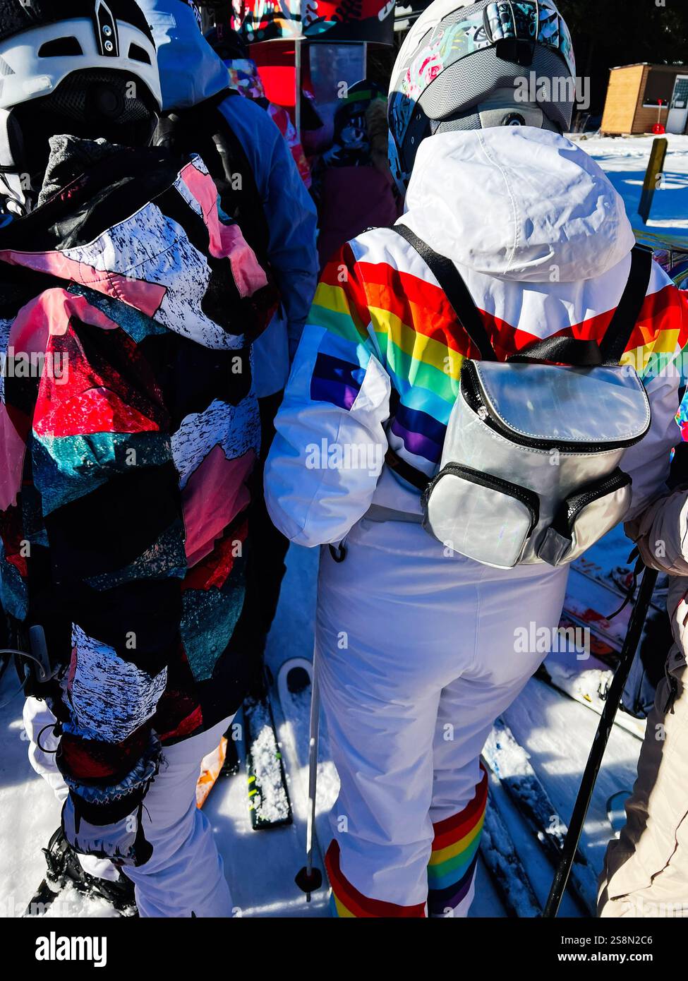 Un gruppo di sciatori in abiti vivaci in fila in una giornata invernale di sole. Foto Stock