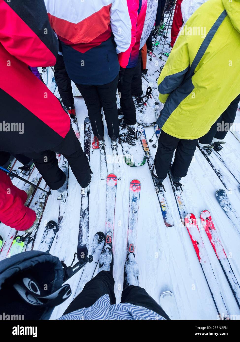 Bukovel, Ucraina - 23 gennaio 2025: Un raduno di sciatori su una collina innevata, catturato da vicino mostrando i loro sci e i vivaci costumi invernali. Foto Stock