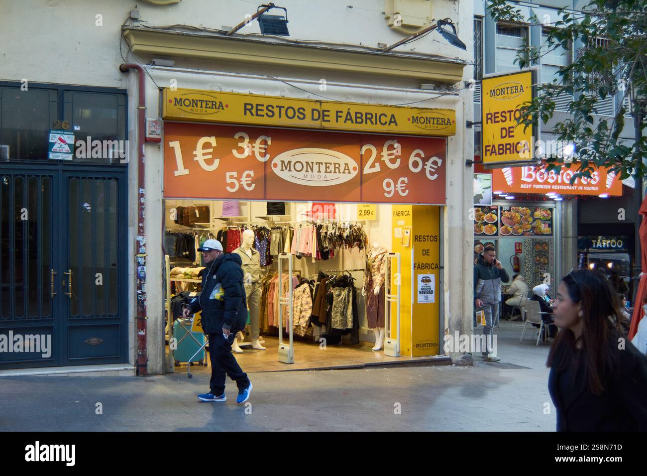 Madrid, Spagna - 23 gennaio 2025: Negozio di abbigliamento economico a Madrid con resti di fabbrica in vendita. La finestra ha grandi cartelli di prezzo e le persone possono essere se Foto Stock