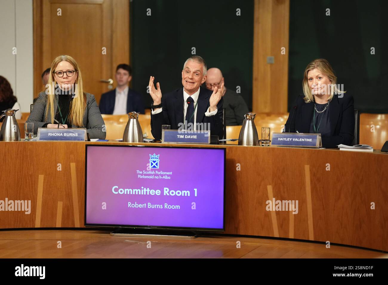 (Da sinistra a destra) Rhona Burns, direttore finanziario della BBC Financial Planning & Insight, Tim DAVIE direttore generale della BBC e Hayley Valentine, direttore della BBC Scotland, rispondendo alle domande sul rapporto annuale della BBC alla Commissione Constitution, Europe, External Affairs and Culture del Parlamento scozzese a Holyrood, Edimburgo. Data foto: Giovedì 23 gennaio 2025. Foto Stock