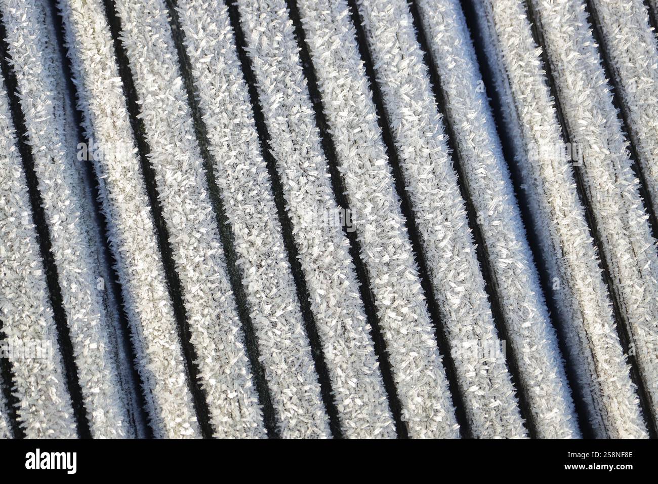 Primo piano di cristalli di ghiaccio sulle spranghe di una struttura in legno. Sfondo con spranghe impostate ad angolo. Foto Stock
