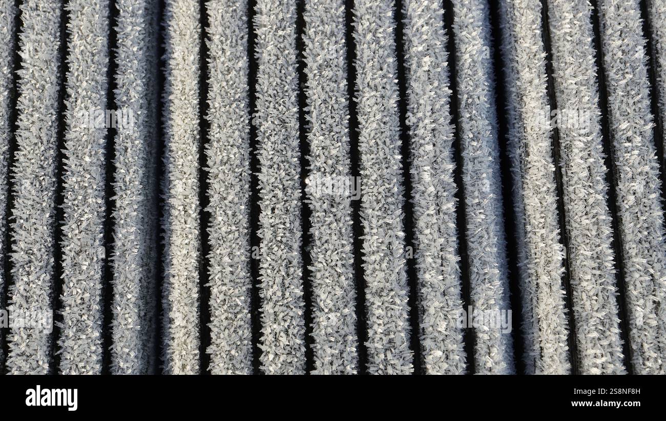 Primo piano di cristalli di ghiaccio sulle spranghe di una struttura in legno. Sfondo con spranghe verticali. Foto Stock