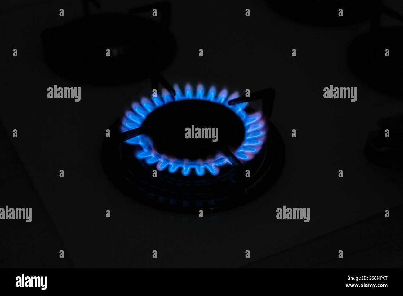 Bruciatore a gas di stufa moderna con fiamma blu che brucia di notte Foto Stock