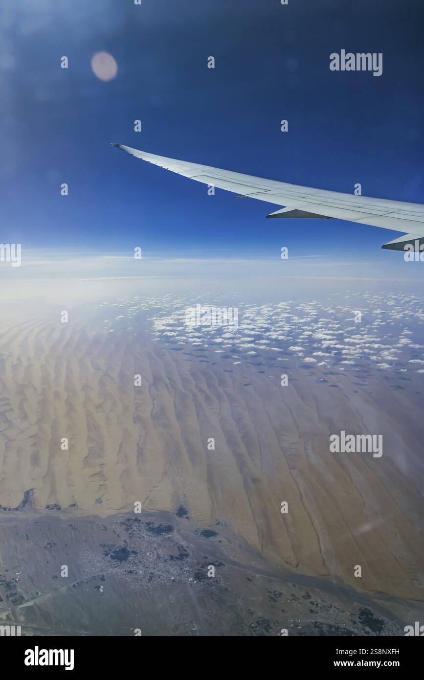 Sopra le nuvole sull'Oman. Vista del deserto dalla finestra dell'aereo durante un volo da Phuket ad Abu Dhabi con la compagnia aerea Etihad. Ala di un Boeing Foto Stock