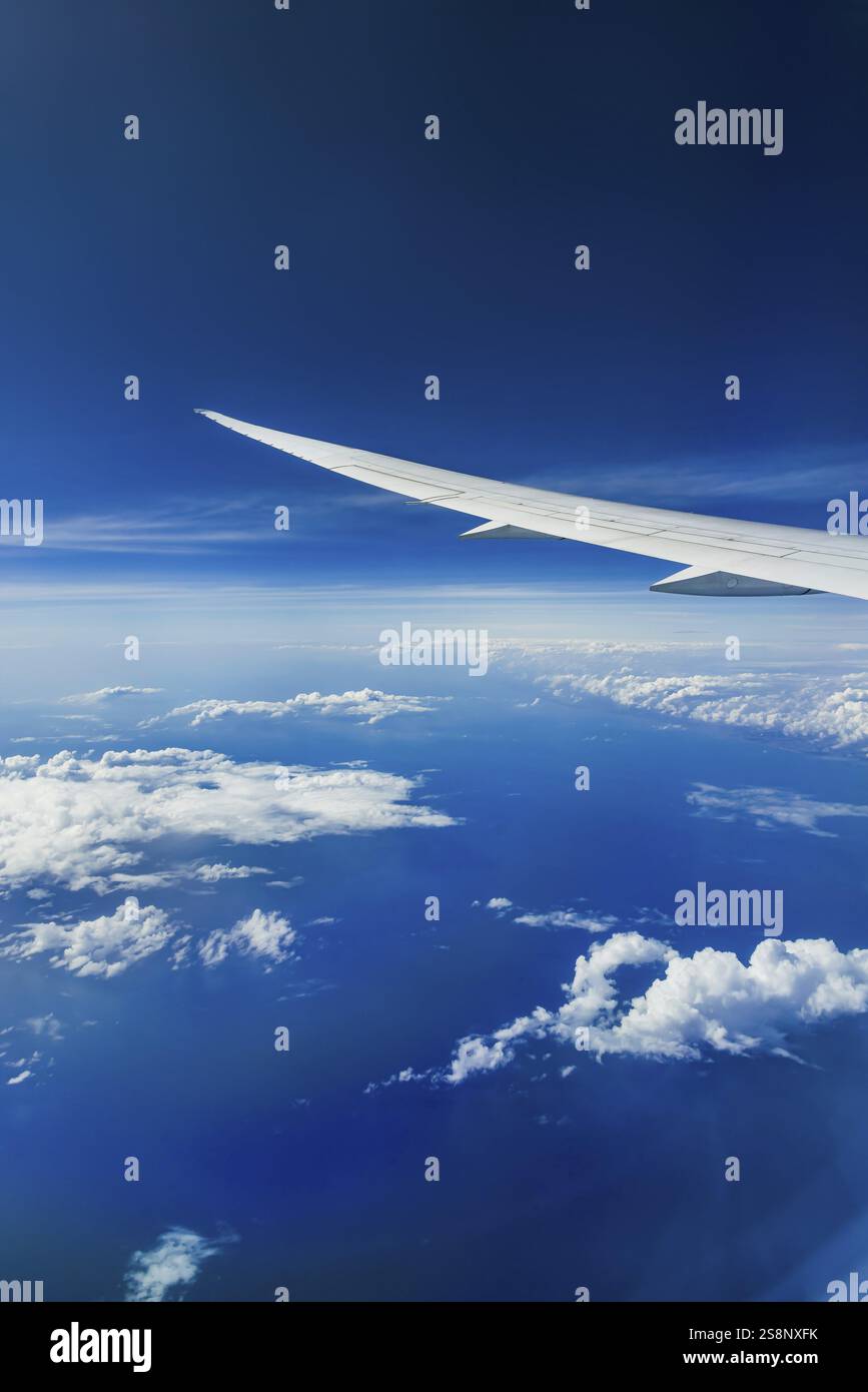 Vista dalla finestra dell'aeromobile durante un volo sull'India con la compagnia aerea Etihad. Cielo blu e strutture nuvolose sul mare, ala di un Boeing 787 Air Foto Stock